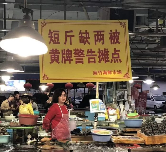 海鲜摊缺斤短两被挂“巨型黄牌”警告，摊主表情亮了(图1)